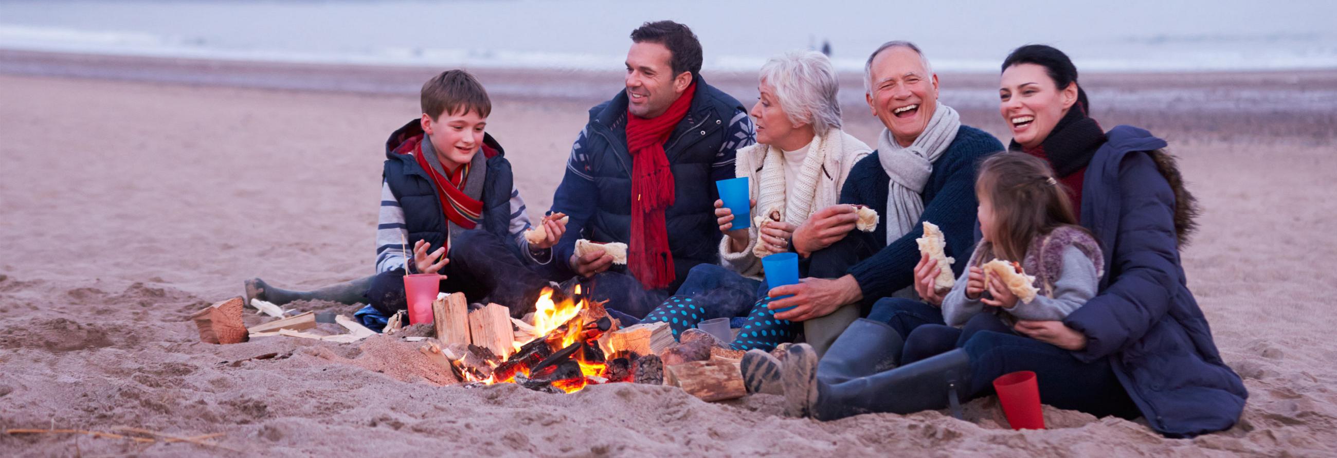 Family laughing around campfire with their 2017 SportTrek Travel Trailer