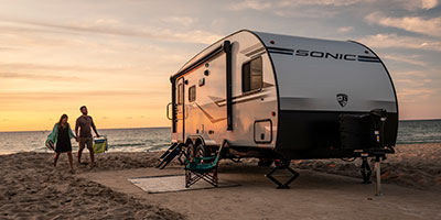 2020 Venture RV Sonic SN210VTB Travel Trailer with couple at beach campsite